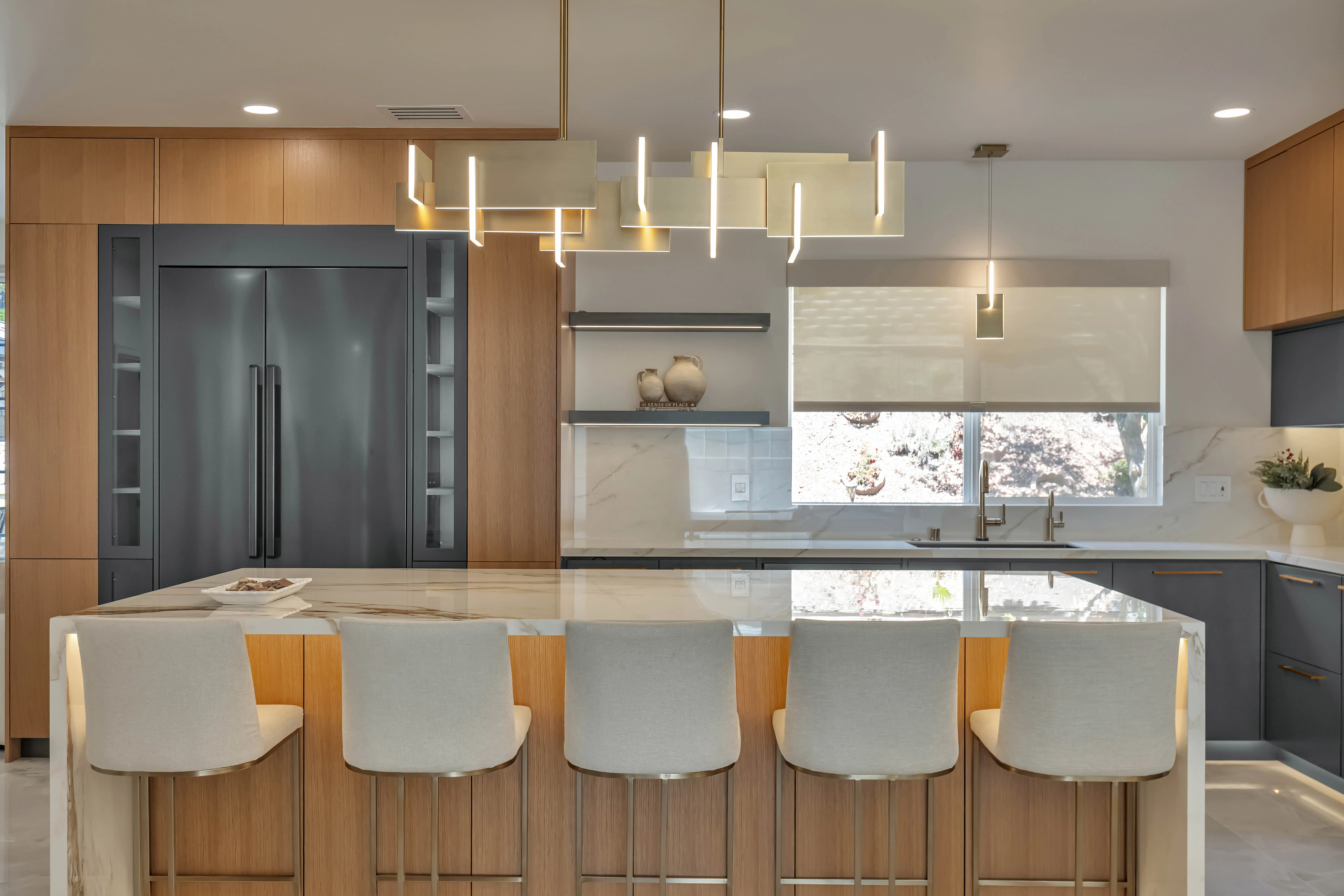 Modern kitchen with white oak cabinetry, marble waterfall island, and custom lighting by Aria Interior Finishes
